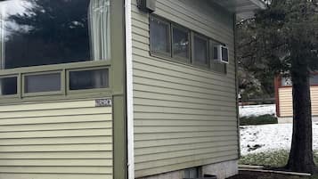 Uma casa térrea com uma placa 'HURON' na lateral, um alpendre coberto e uma árvore na frente.