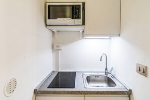A compact kitchen with a built-in microwave, a sink, and an induction cooktop. - Al Portico (Avola)
