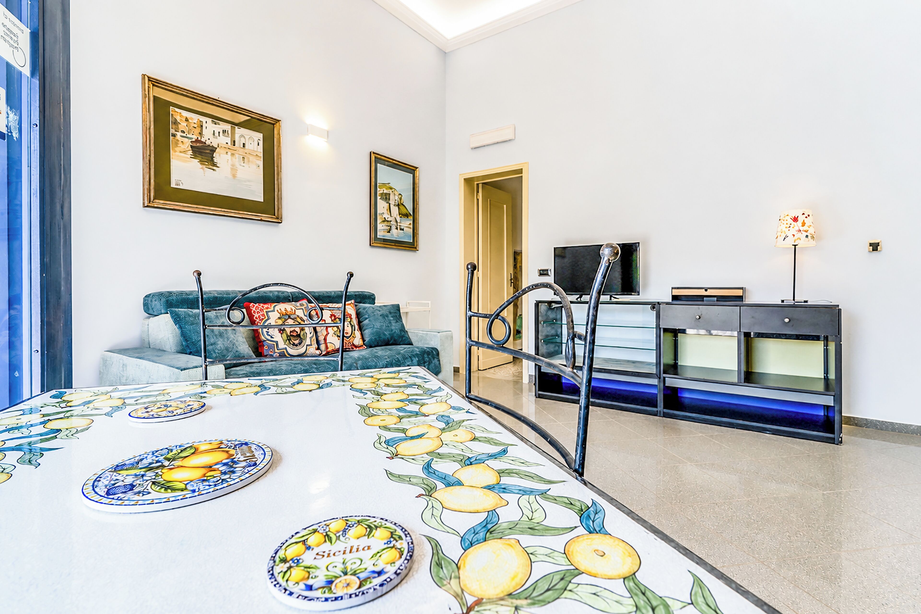 A living room with a sofa, a table with fruit designs, a television, and a cabinet.