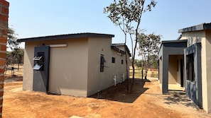 A building with a flat roof, a door, and windows. There is a tree in front of the building.