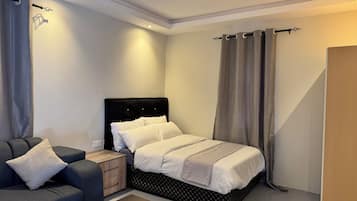 A bedroom with a bed, a nightstand, a sofa, and a wooden door.