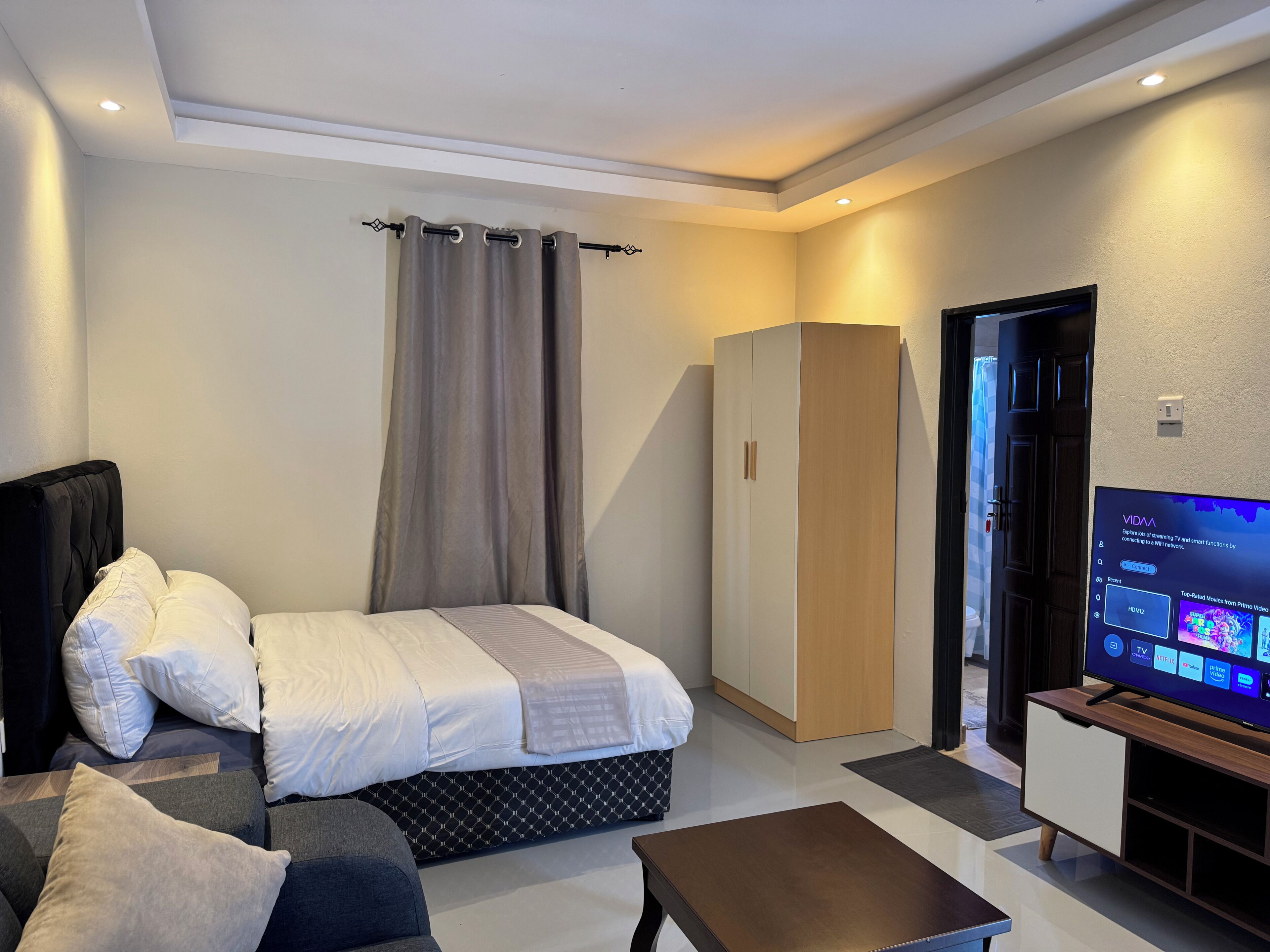 Ein modernes Hotelzimmer mit Bett, Sofa, Fernseher und Kleiderschrank.