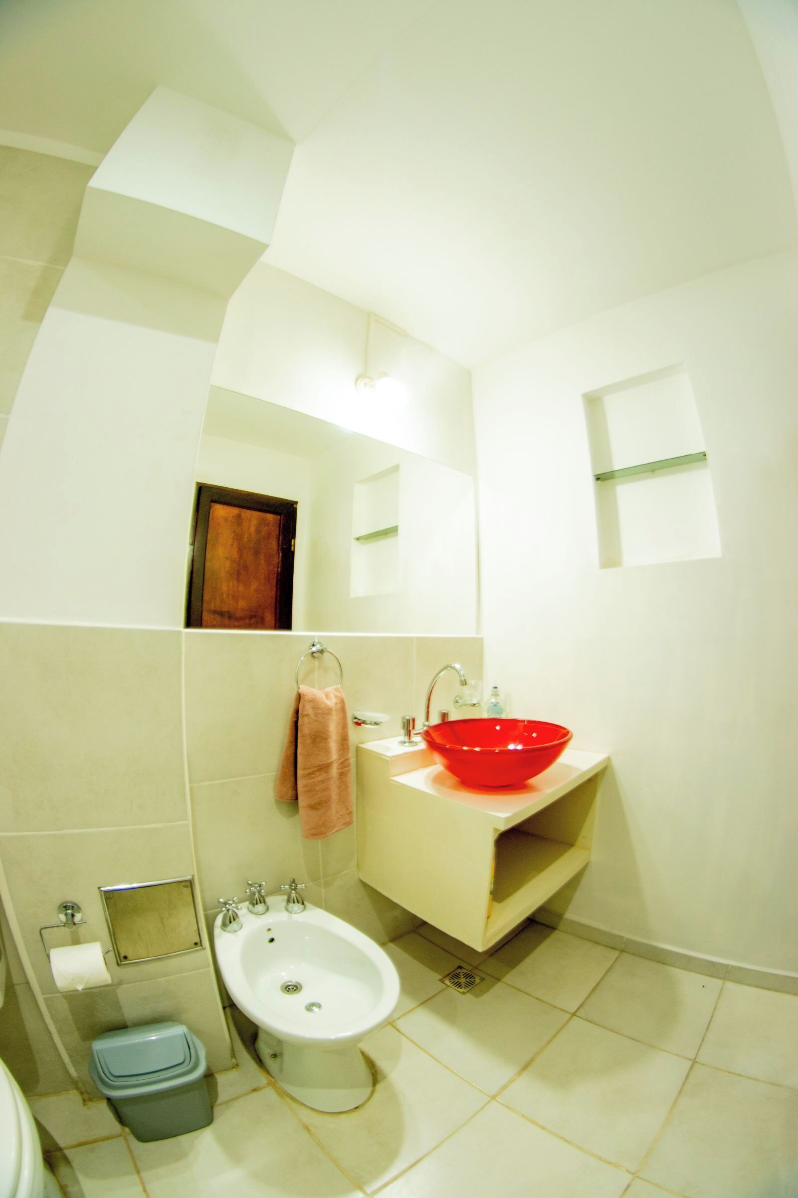 A bathroom with a white sink, a bidet, a toilet, and a mirror.