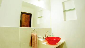 A bathroom with a white sink, a bidet, a toilet, and a mirror.