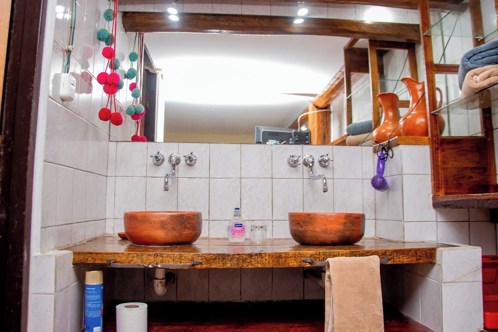 A bathroom with two copper sinks, a mirror, and a towel rack.