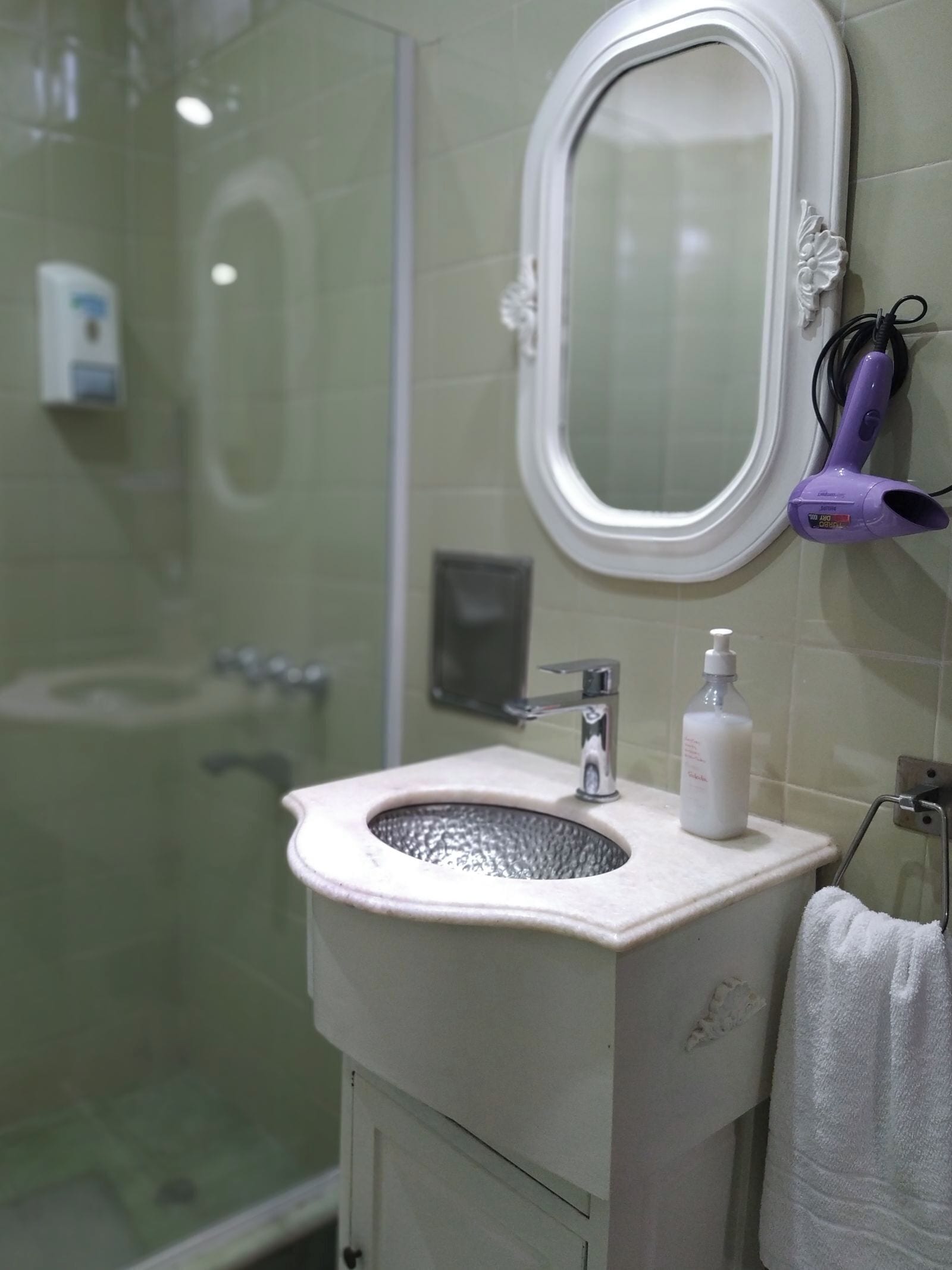 Un baño con cabina de ducha de vidrio, un lavabo blanco con grifo plateado y un espejo sobre el lavabo.