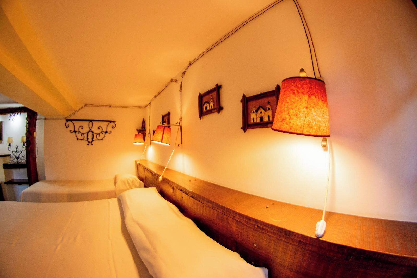 Habitación de hotel con dos camas, cabecero de madera, lámparas de pared y un adorno mural.
