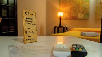 Habitación de hotel con un cartel de recepción, una cama, una lámpara y dos controles remotos sobre la mesa.