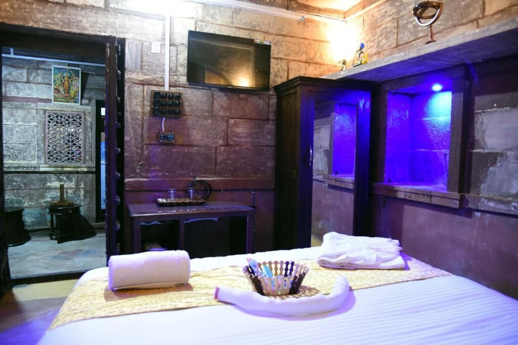 Habitación de hotel con cama, una mesita, un televisor y un adorno en la pared.