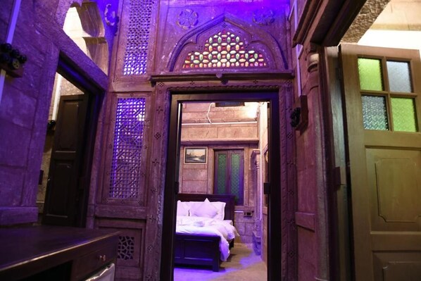 A narrow hallway leading to a room with a bed and a window.