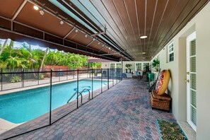 Ein Poolbereich mit Überdachung und freiem Blick auf den Pool, eine Sitzgelegenheit mit Tisch und Stühlen sowie ein dekorativer Gegenstand auf einem Podest.