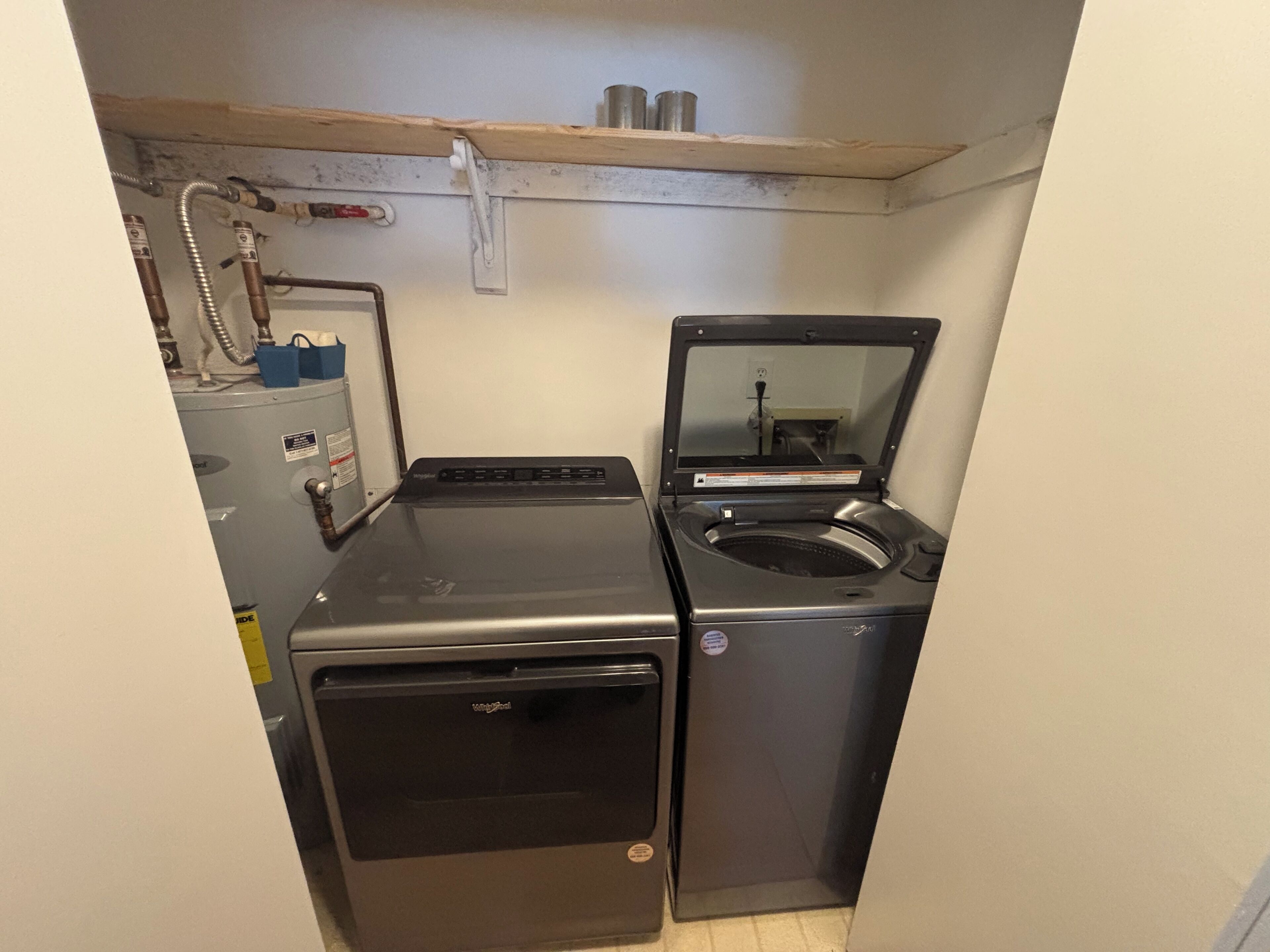 A compact laundry room with a front-loading washer and a top-loading dryer.