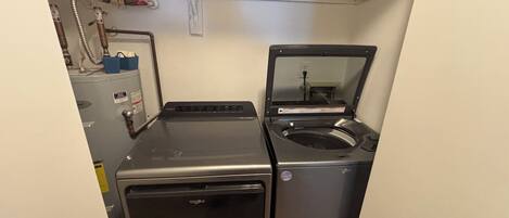 A compact laundry room with a front-loading washer and a top-loading dryer.