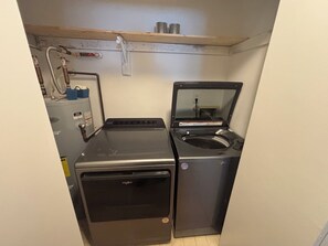 A compact laundry room with a front-loading washer and a top-loading dryer. - Enjoyable 2-bedroom condo with AC in charming Pensacola (Pensacola)