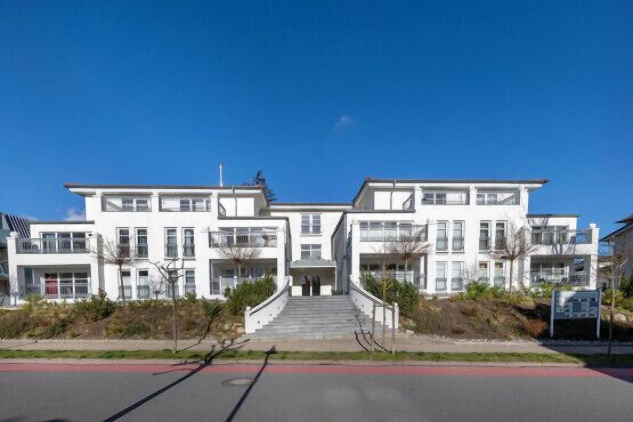 A modern building with a central staircase leading to a flat entrance.