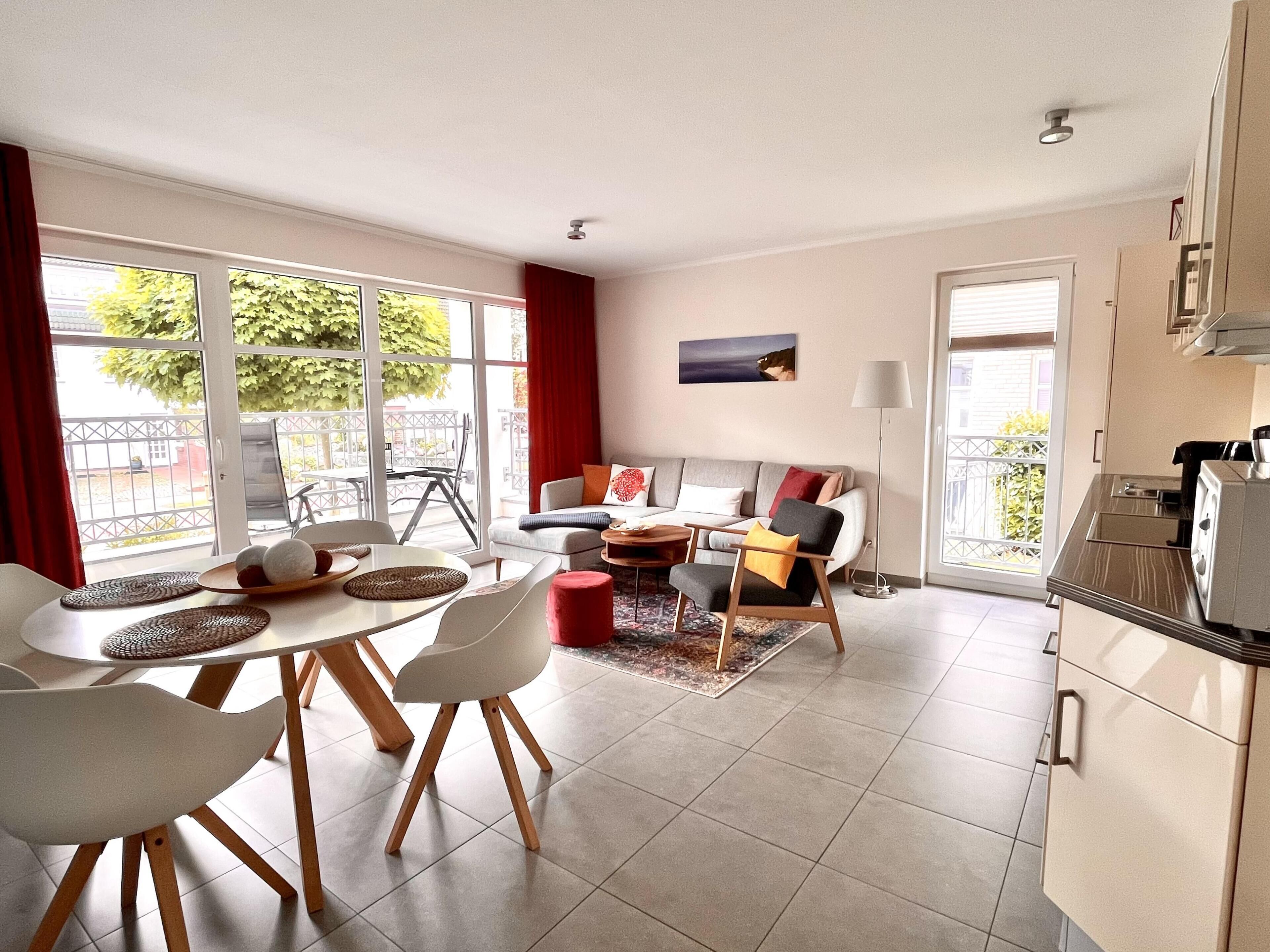 A modern living room with a dining area, a sofa set, and a kitchen with a built-in oven.