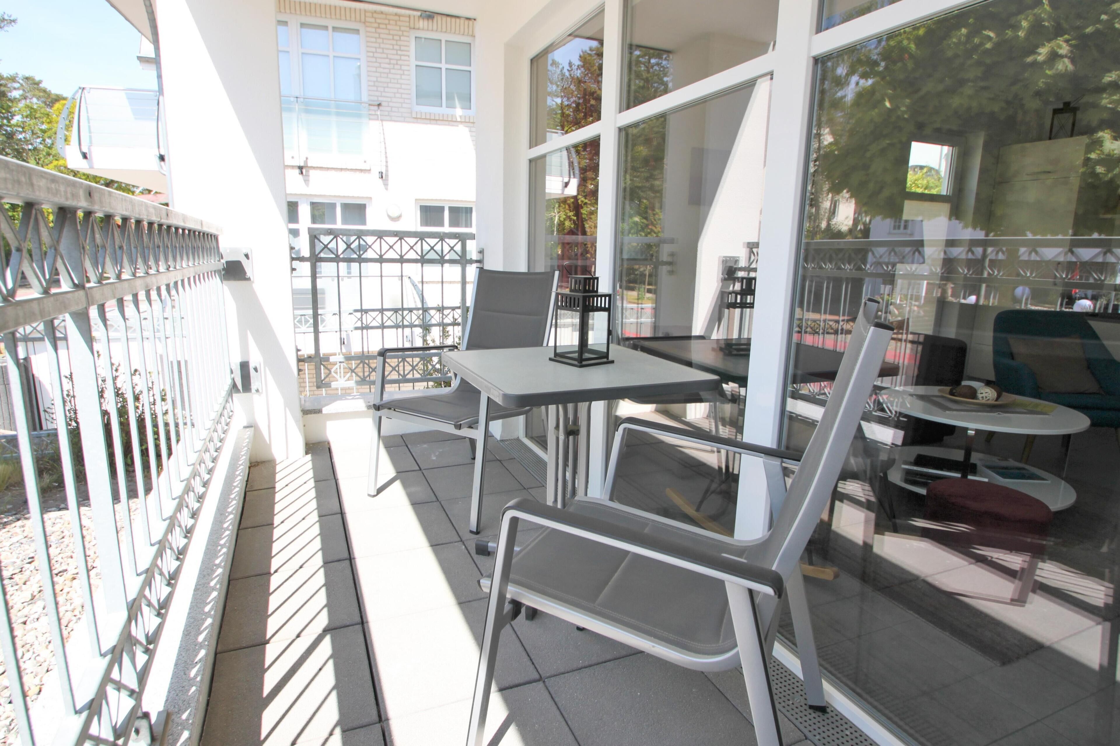 An outdoor seating area with a table and chairs, a glass partition, and a view of the street.