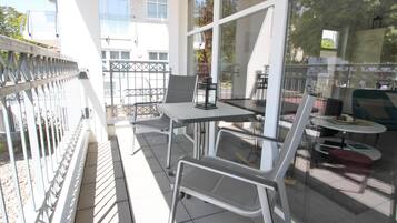 An outdoor seating area with a table and chairs, a glass partition, and a view of the street.