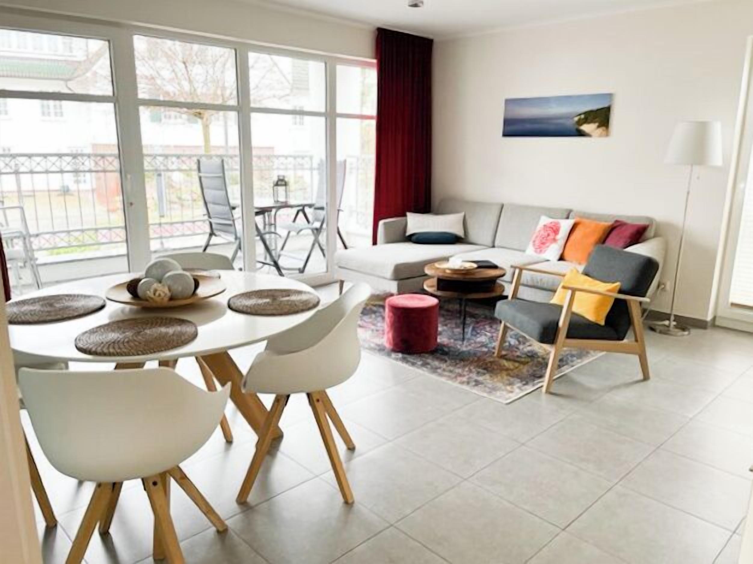 A modern living room with a dining area, large windows, and a view of the outdoors.