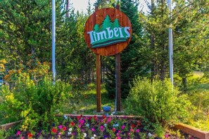 Ein Schild mit der Aufschrift 'Timbers', umgeben von einem Garten mit verschiedenen Pflanzen und Blumen.