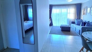 Et hotelværelse med seng, sofa, spisebord og spejl.