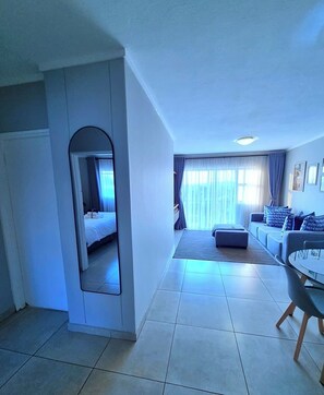 Una camera d'albergo con un letto, un divano, un tavolo da pranzo e uno specchio.