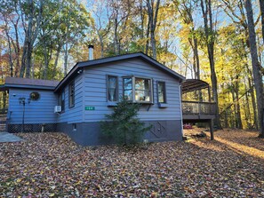 Une cabane à deux étages, portant le numéro « 104 » sur le côté, entourée d’une forêt aux feuilles d’automne.
