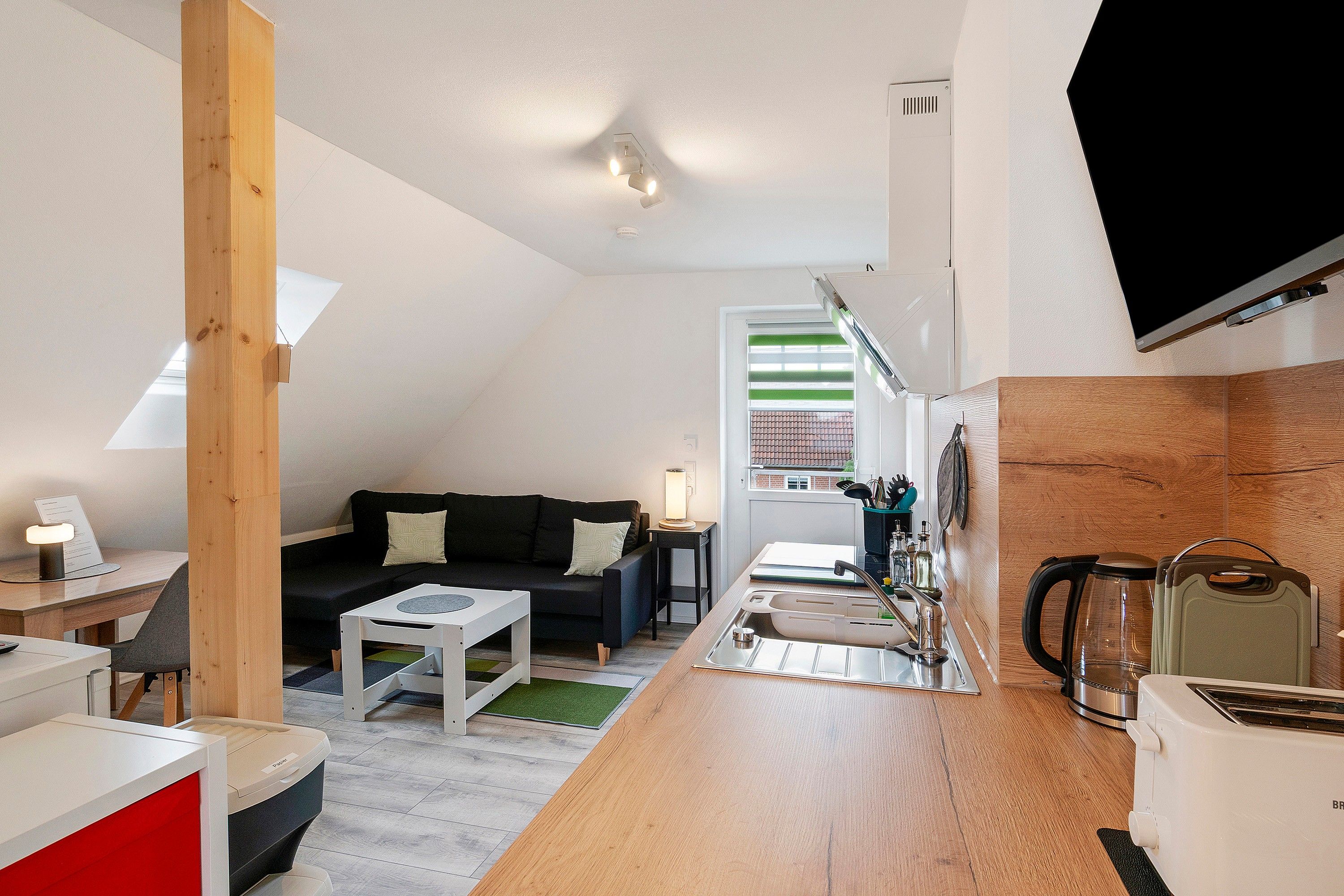 Un espace de vie compact comprenant un coin cuisine, un coin repas et un coin salon avec un canapé et une table basse.