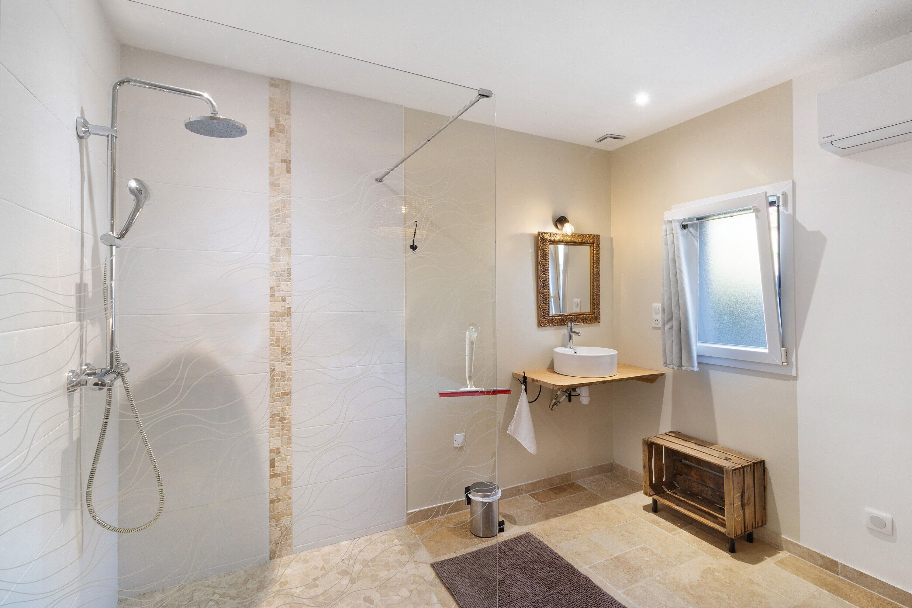 Une salle de bain moderne équipée d’une douche, d’un lavabo, d’un miroir et d’une fenêtre.