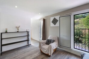 A modern living room with a large window, a sofa, a wooden floor, and a decorative wall piece. - Holiday Home 'Maison De Vacances L Etable' with Private Pool, Wi-Fi and Air Conditioning (Coly-Saint-Amand)