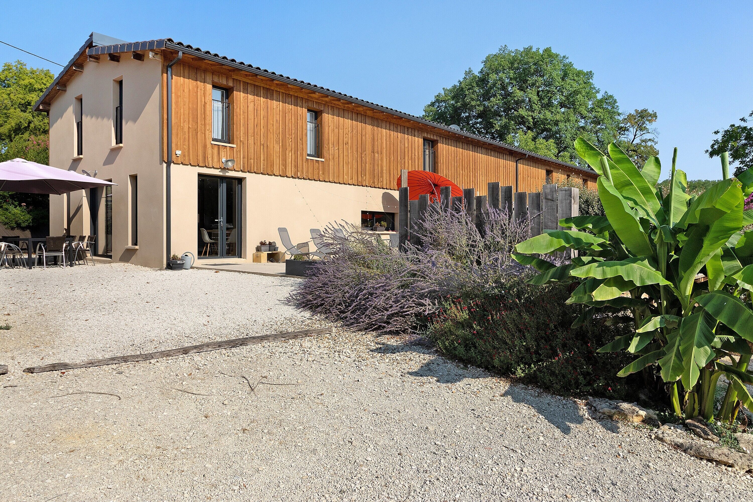 Un bâtiment à deux étages avec une allée en gravier et une clôture en bois.