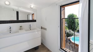 Une salle de bain avec deux vasques, un miroir et une fenêtre donnant sur une piscine.