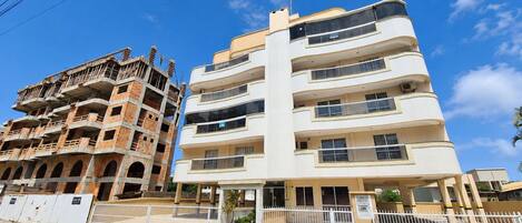 A multi-story building with balconies and a gated entrance.