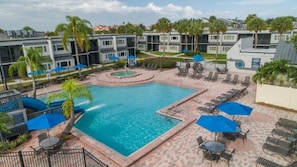A swimming pool with lounge chairs and umbrellas, surrounded by a brick patio and palm trees. - Peaceful Stay | Pool+Garden Area, Views, BBQ (Kissimmee)