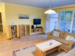 Ein Wohnzimmer mit einer Couch, einem Couchtisch, einem Fernseher und einem Bücherregal.