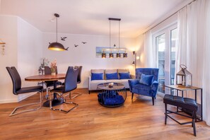 Un salon moderne comprenant un coin repas, un canapé, un fauteuil bleu et une table basse.