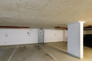 Eine Tiefgarage mit Betonböden, weißen Wänden und nummerierten Stellplätzen.