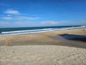 A beach with a wide sandy area, a small water channel, and gentle waves. - Villa Jeanne, your ideal vacation home just a stone's throw from the beach in Salento! (Presepe)