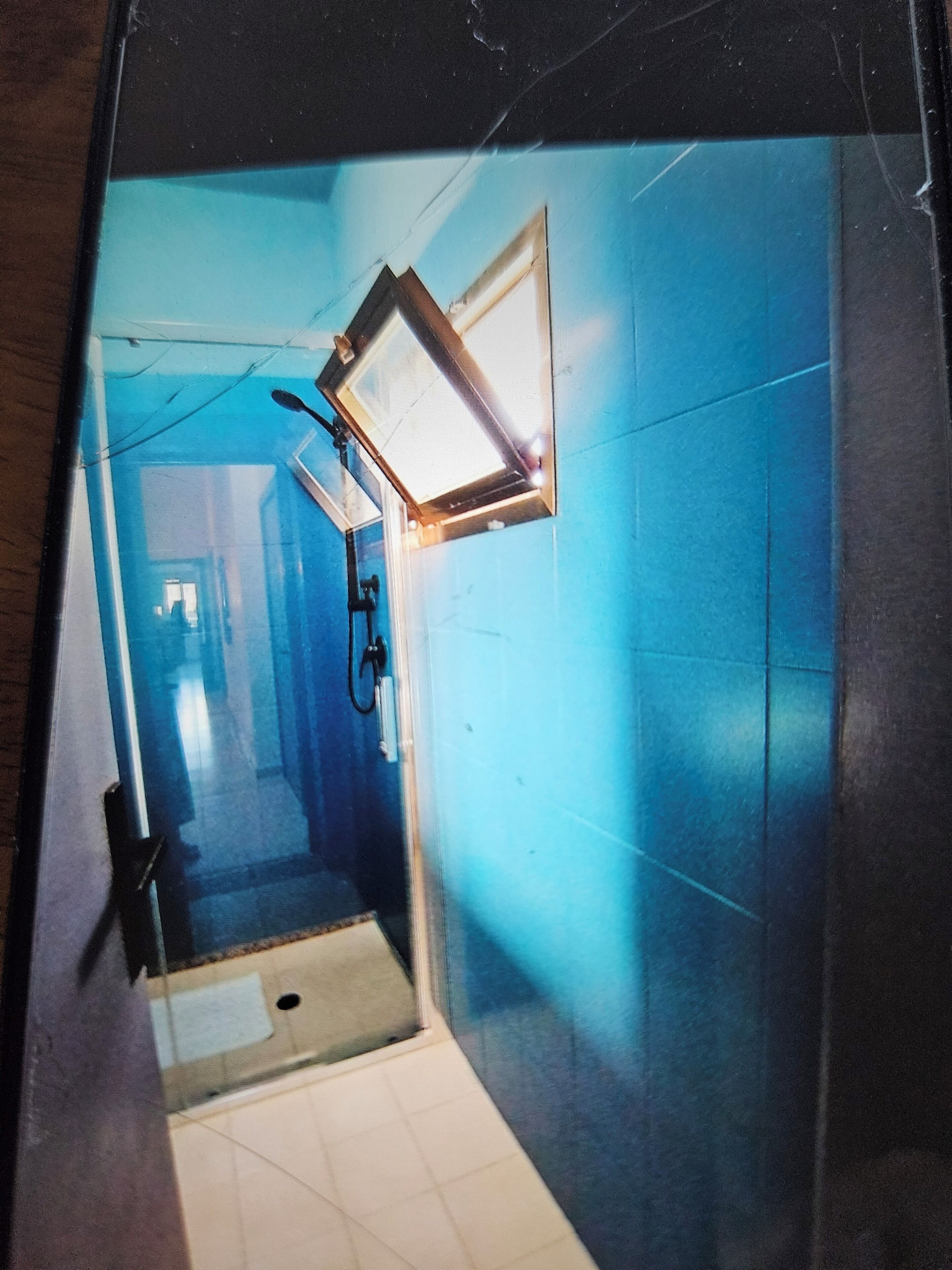 A corridor with a blue wall, a light fixture, and a door at the end.