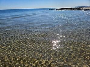 Agua clara y poco profunda con el sol reflejado en la superficie.