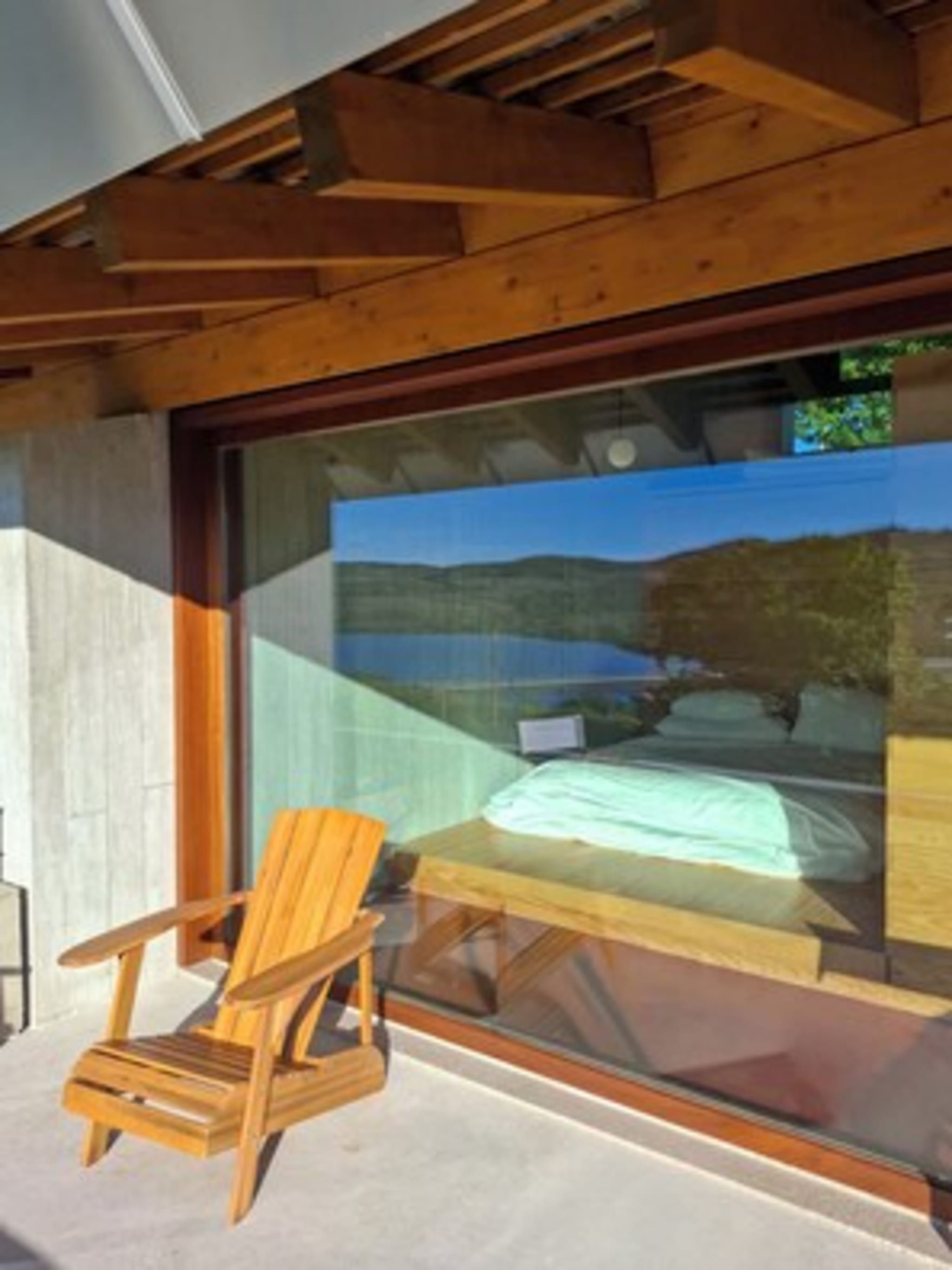 Una silla de madera y una mesa en una habitación con un ventanal grande.