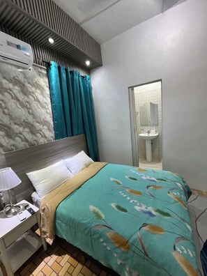 A hotel room with a bed, a nightstand, a lamp, a mirror, and a bathroom visible through a door. - Spacious apartment in Zona Colonial. Walking distance to city Promenade (Distrito Nacional)