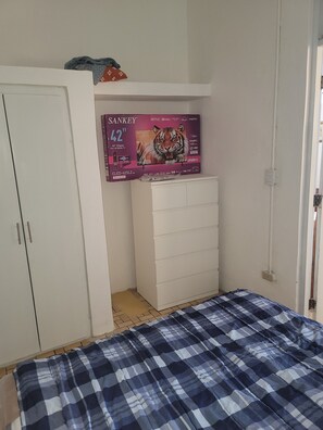 Ein Schlafzimmer mit einem Bett, einem Kleiderschrank und einem Fernseher an der Wand.