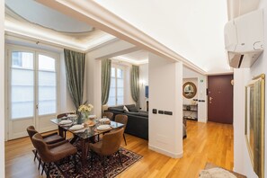 A well-lit room with a dining table set for four, a sofa, and a kitchen area visible through an open doorway. - Churchkey by Rent All Como (Como)