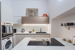 A compact kitchen with a built-in washing machine, a microwave, a kettle, and a sink. - Churchkey by Rent All Como (Como)