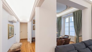 A modern living room with a sofa, a dining area with a table set for two, and a hallway with framed pictures. - Churchkey by Rent All Como (Como)