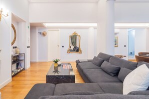 A modern living room with a grey sofa, a marble coffee table, and a mirror with a gold frame. - Churchkey by Rent All Como (Como)