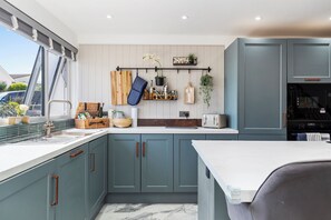 Une cuisine avec des meubles de couleur turquoise, un plan de travail blanc et une plante suspendue.