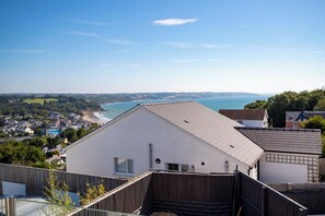 Un immeuble résidentiel doté d’un toit en pente, d’une petite fenêtre et offrant une vue sur un paysage côtier.