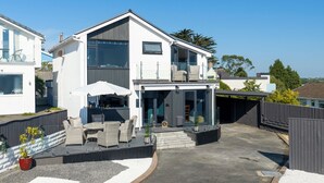 Een modern huis met twee verdiepingen, een balkon, buitenmeubilair en een garage.